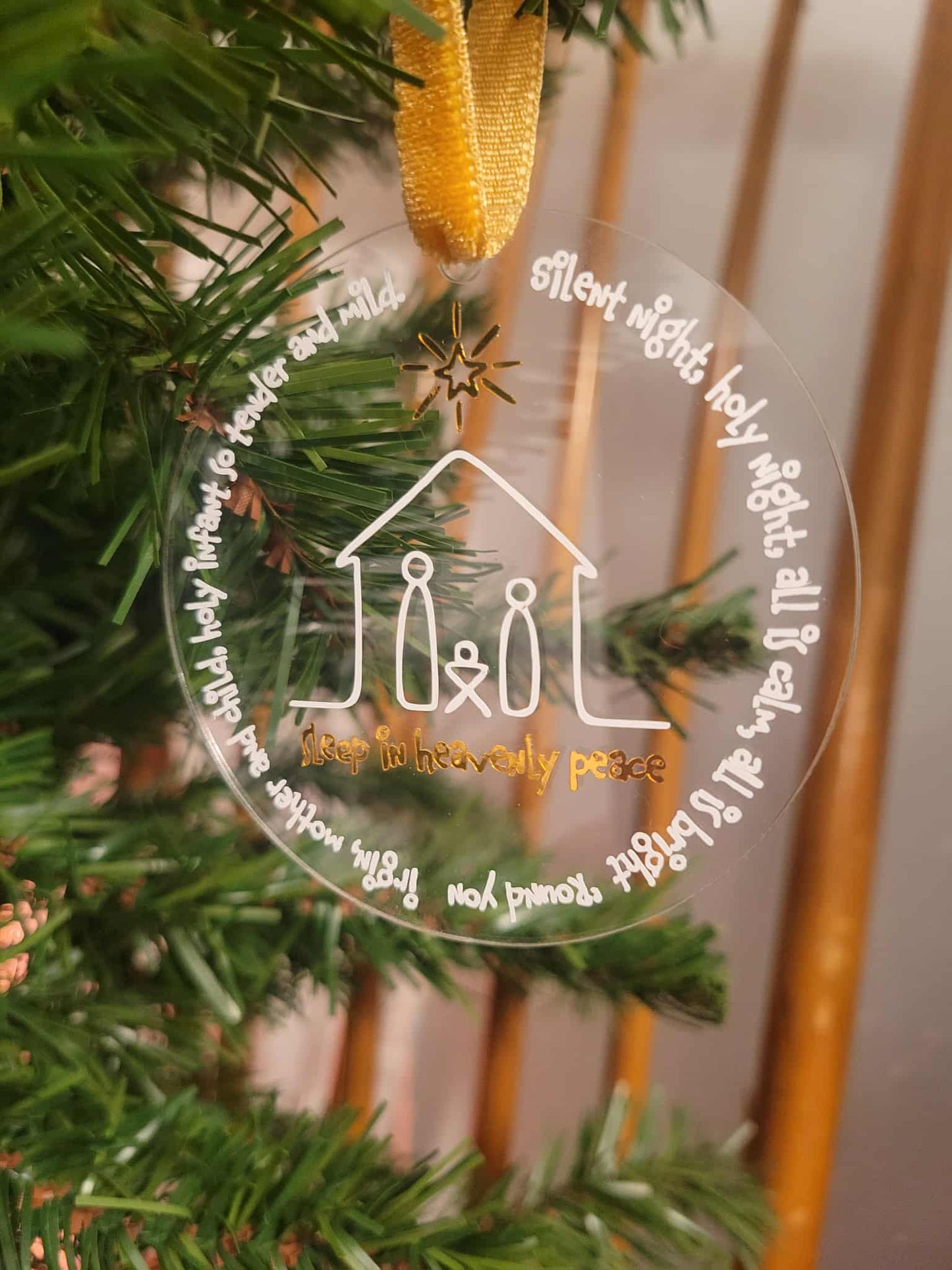 Decorative Christmas ornament with text and a house illustration on a green wreath.