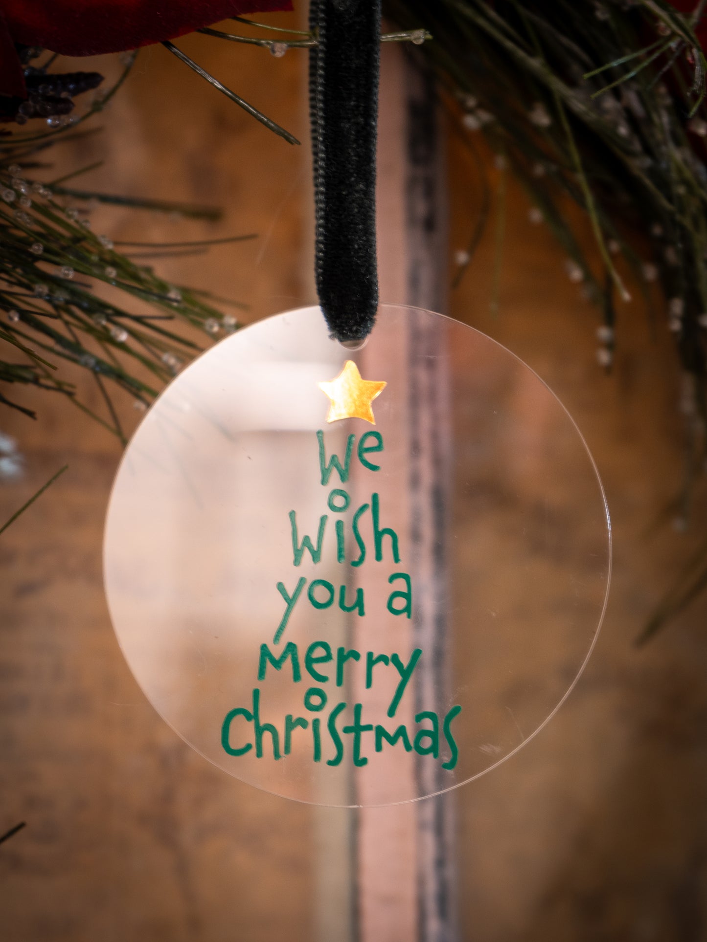 Christmas ornament with 'We wish you a Merry Christmas' text on a blurred background