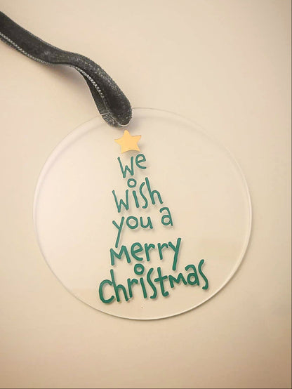 Round Christmas ornament with 'We wish you a Merry Christmas' text on a beige background