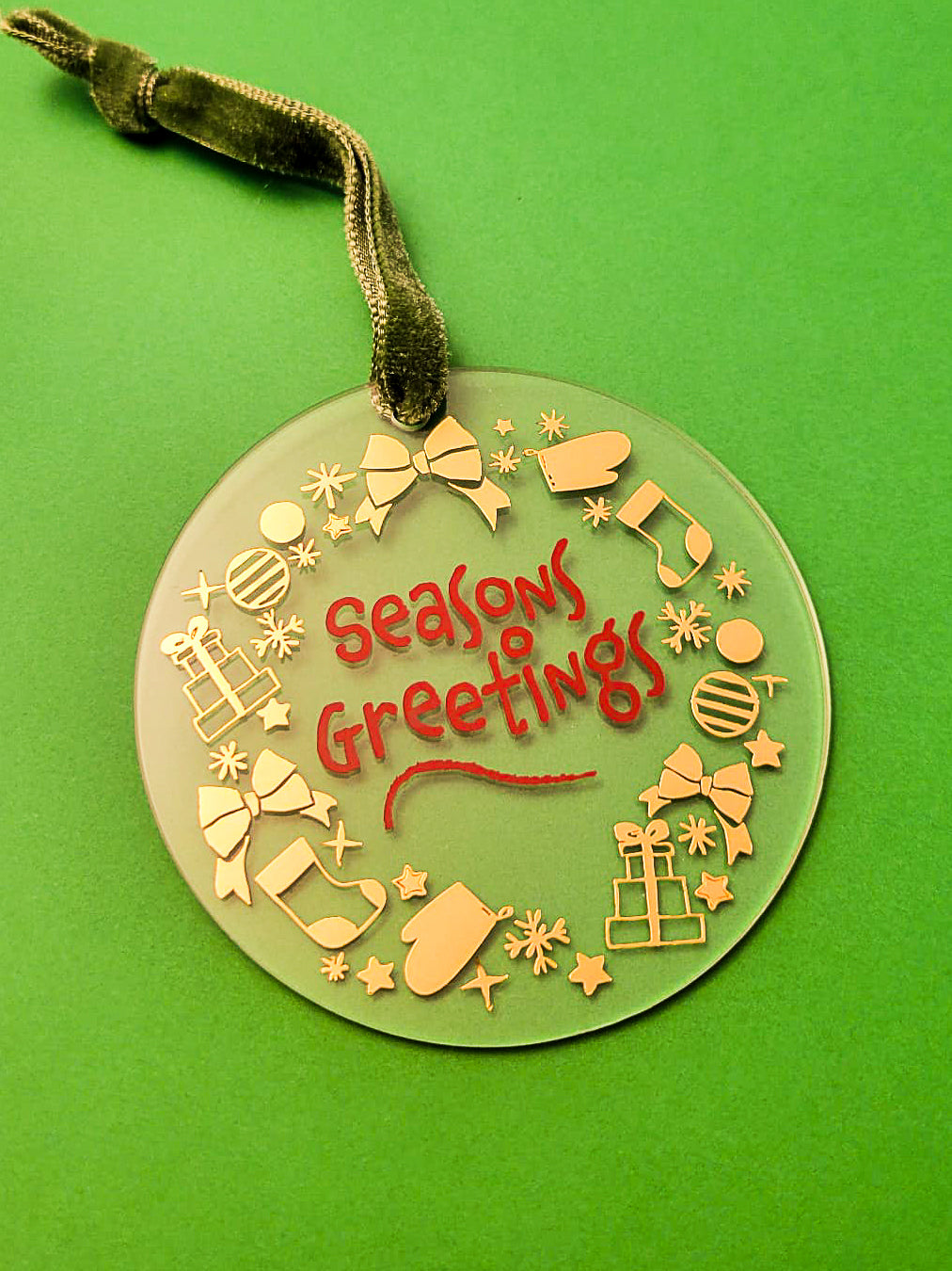 Decorative Christmas ornament with 'Seasons Greetings' text on a green background