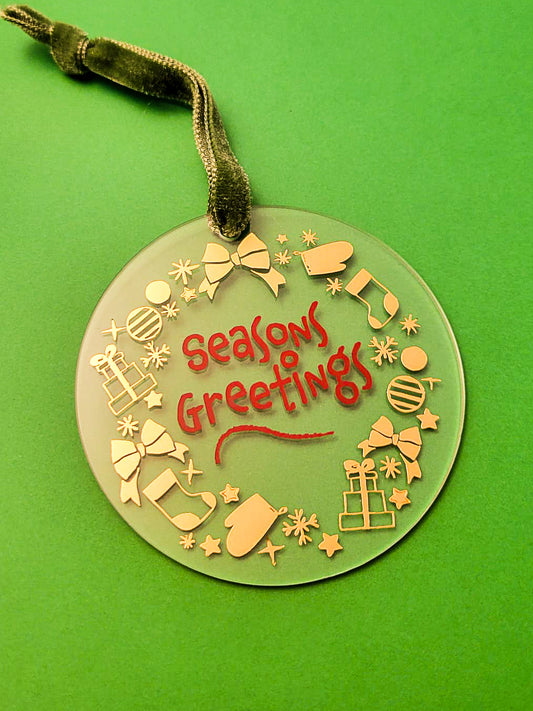 Decorative Christmas ornament with 'Seasons Greetings' text on a green background