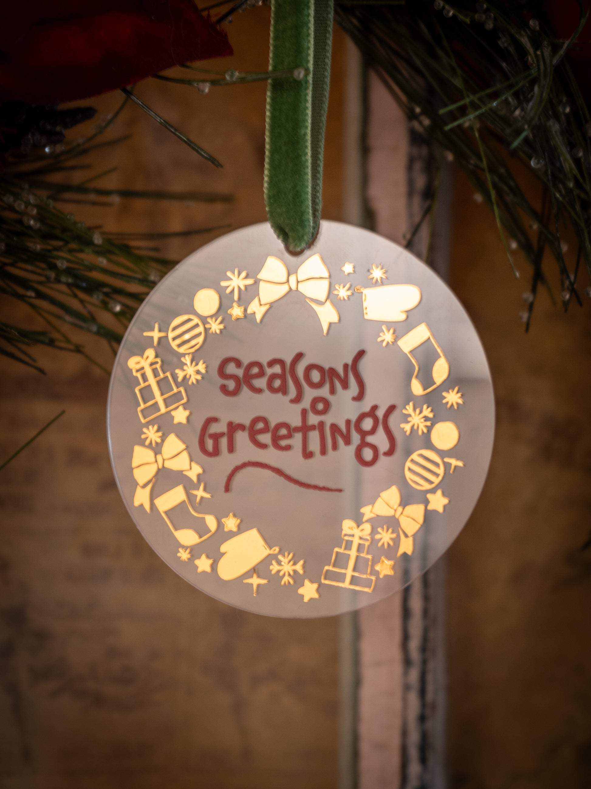 Decorative Christmas ornament with 'Seasons Greetings' text on a tree.