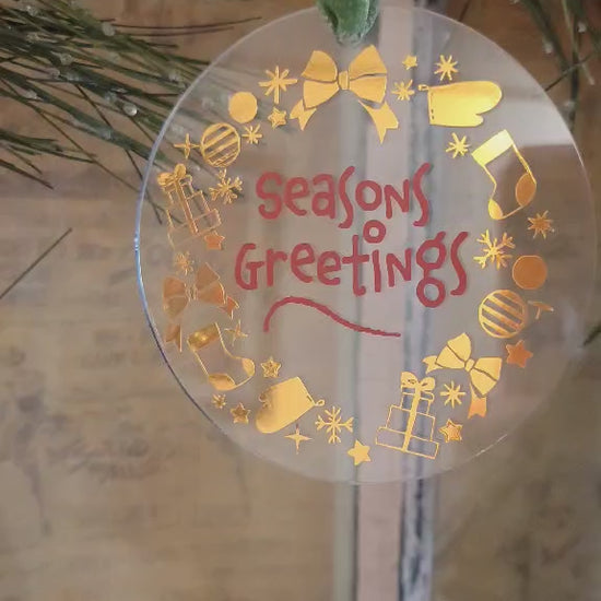 Video showing the lighting on a clear acrylic round ornament with gold and red vinyl hanging on a wreath